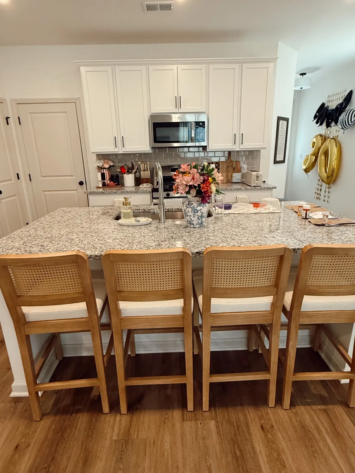 Lo’s complete kitchen photo, with warm wood, cane stools and flowers